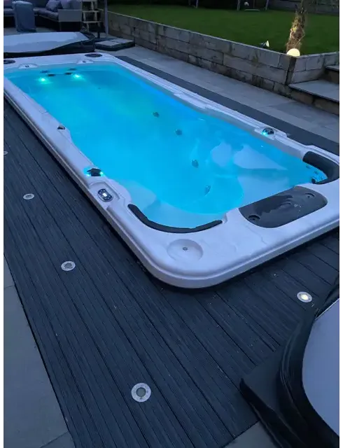 Vit PassionSpa Aquatic 2 Swim Spa med vit rektangulär form, blått upplyst vatten och svarta accenter