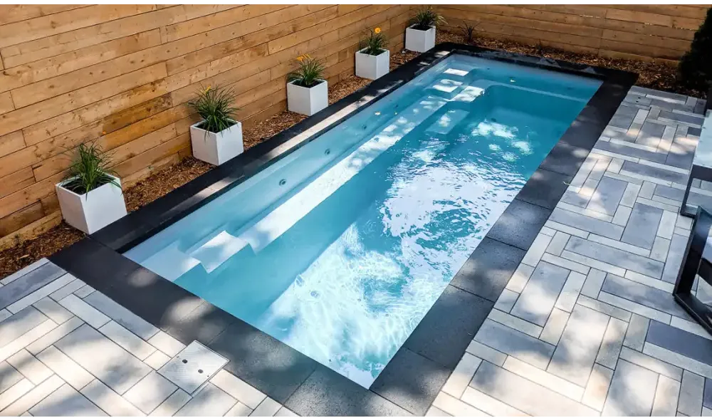 Leisurepools Espirit med slimmad form för trängre utrymmen, rektangulär pool med klart blått vatten och svarta kakelkanter