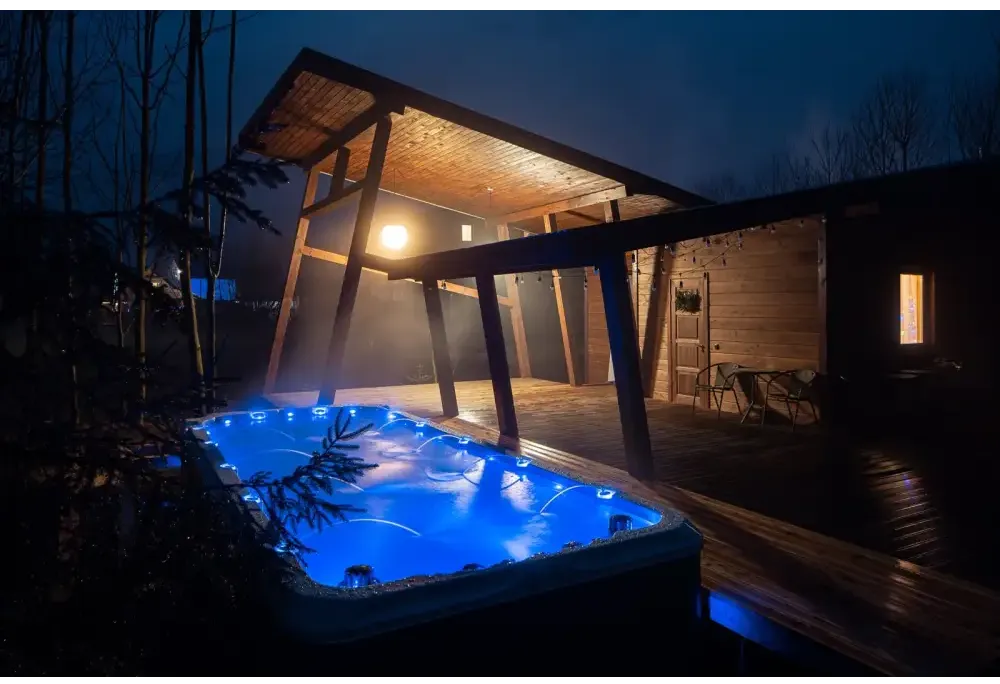 Blå upplyst PassionSpa Activity 2 Deep Swim Spa med trädeck och täckt patio