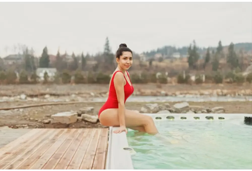 Kvinna i röd baddräkt sitter vid PassionSpa Activity 2 Deep Swim Spa