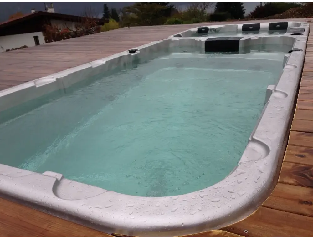 Vit PassionSpa Aquatic 3 Deep Swim Spa med vit rektangulär form, svarta säten och turkost vatten på trädeck