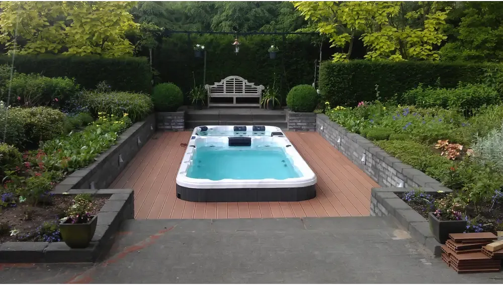Vit PassionSpa Aquatic 3 Deep Swim Spa i svart och vitt med turkost vatten, trädäck och trädgård