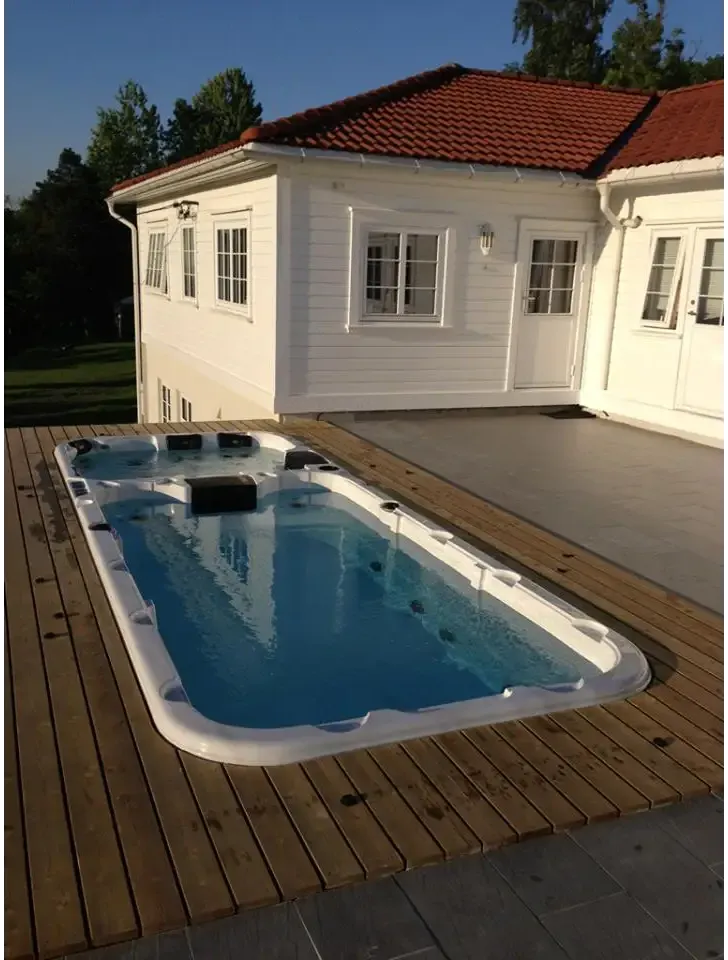 Vit PassionSpa Aquatic 3 Swim Spa med vit rektangulär form, blått vatten och svarta sittdynor på trädäck