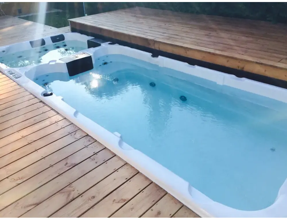 Vit PassionSpa Aquatic 3 Swim Spa – Sport Collection, vit rektangulär med blått vatten och svarta jetstrålar på trädeck