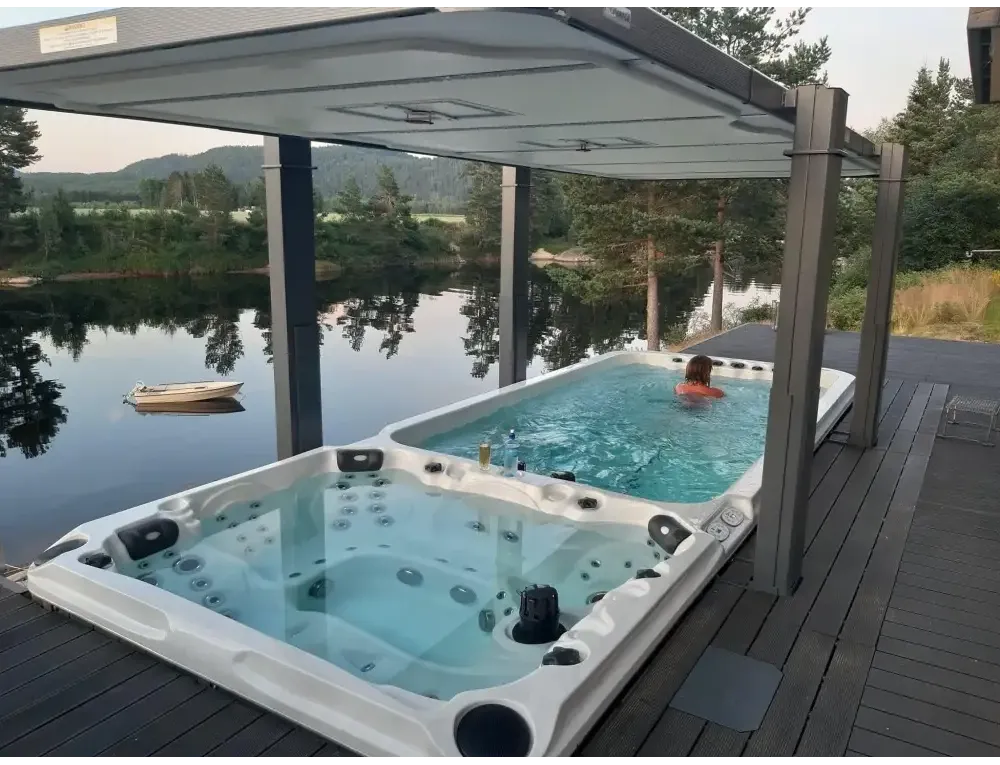 Vit PassionSpa Dynamic Swim Spa – Sport Collection, vit badkar med svarta jetstrålar under grå tak på trädeck