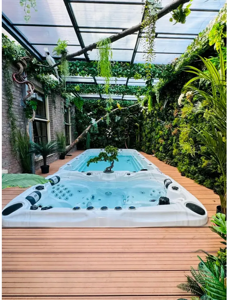 Vit PassionSpa Spirit Deep Swim Spa i Sport Collection, vit med svarta jetstrålar i grönska under transparent tak