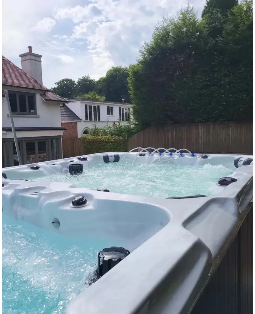 Snygg ljusgrå PassionSpa Vitality Swim Spa med bubblande turkost vatten och svarta jetstrålar