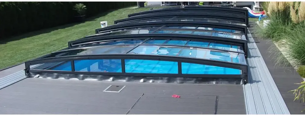 Pooltaket Special med RAL7016 antracit profiler, svart ramad med transparenta paneler över blå poolvatten