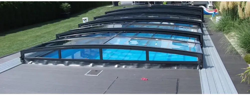 Pooltak special med böjd glasdesign och svart ram över blå pool