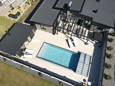 Rektangulär pooltime exklusiv 12mm pp pool 2,6 x 6 x 1,5 m med klart blått vatten och beige pooltak omgiven av mörkgrå takstruktur
